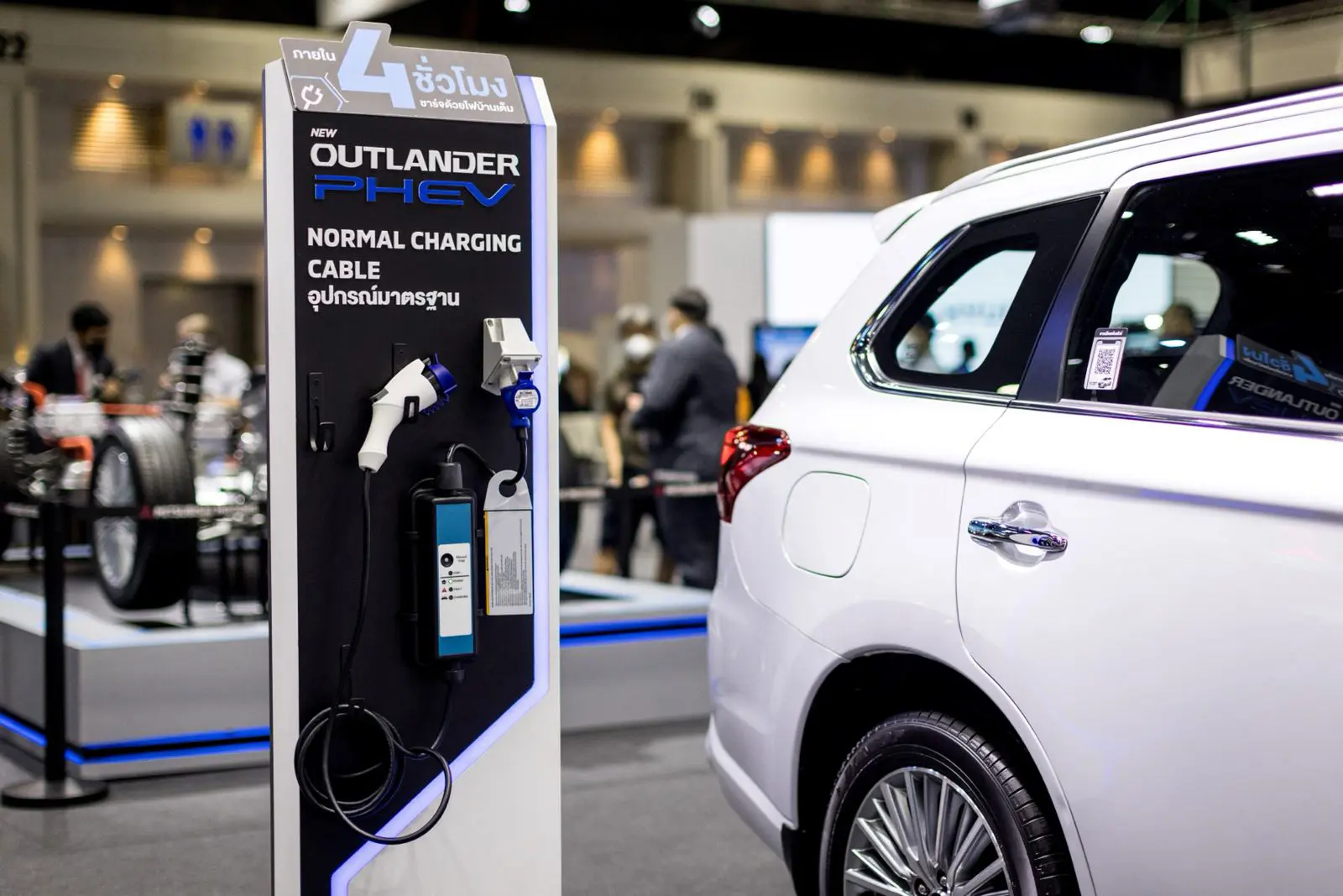 مكونات الشحن بجوار سيارة ميتسوبيشي أوتلاندر PHEV الهجينة القابلة للشحن في معرض تايلاند الدولي للسيارات 2021 في بانكوك
